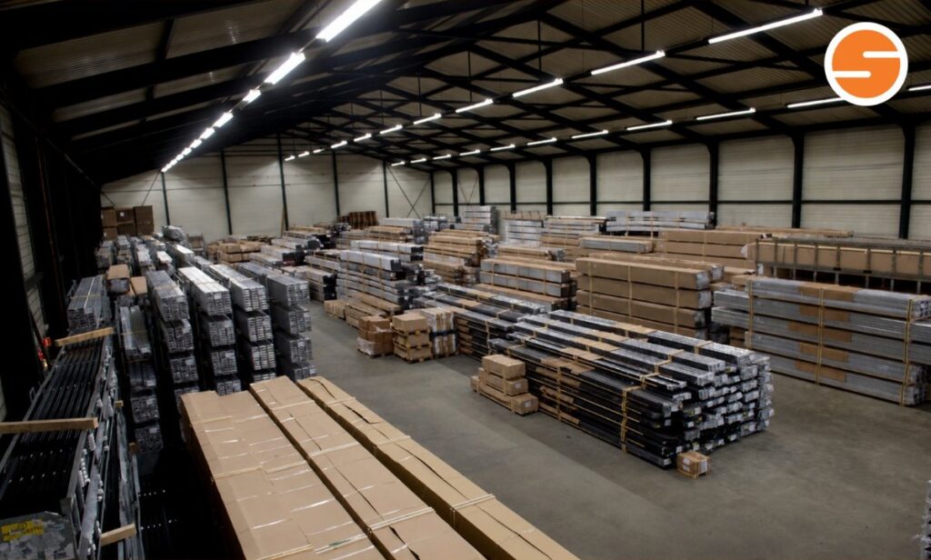 Bundels metalen profielen en lange pakketten op de vloer van het warehouse in Hoogezand